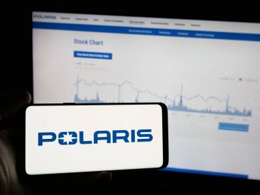 Stuttgart, Almanya - 12-11-2024: Web sitesinin önünde ekranda ABD 'li otomotiv şirketi Polaris Inc.' in logosuna sahip akıllı telefonu tutan kişi. Telefon ekranına odaklan.