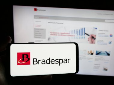 Stuttgart, Almanya - 12-13-2024: Brezilyalı holding şirketi Bradespar SA 'nın logosunu elinde tutan kişi web sitesinin önünde ekranda. Telefon ekranına odaklan.
