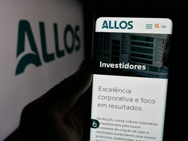 Stuttgart, Almanya - 12-13-2024: Brezilyalı gayrimenkul geliştirme şirketi Allos SA 'nın internet sayfası ile cep telefonu tutan kişi logolu ekranda. Telefon ekranının merkezine odaklan.
