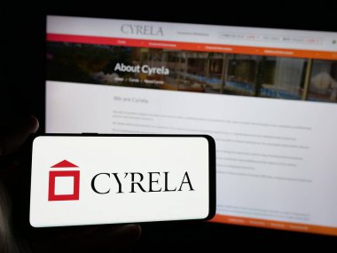 Stuttgart, Almanya - 12-16-2024: Brezilyalı şirket Cyrela Brazil Emlak SA 'nın logosuna sahip akıllı telefon sahibi kişi web sitesinin önünde ekranda. Telefon ekranına odaklan.