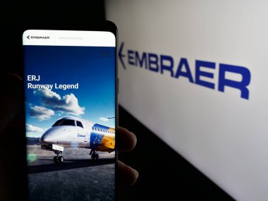 Stuttgart, Almanya - 12-16-2024: Brezilyalı havacılık şirketi Embraer SA 'nın web sayfası olan cep telefonu logosu önünde ekranda. Telefon ekranının merkezine odaklan.