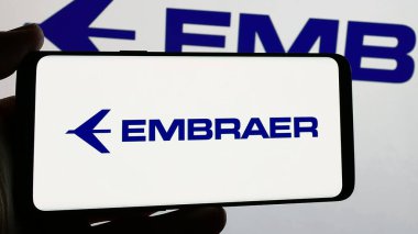 Stuttgart, Almanya - 12-16-2024: Ekranda Brezilyalı havacılık şirketi Embraer SA 'nın logosunu tutan kişi. Telefon ekranına odaklan.