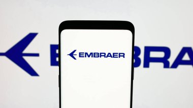 Stuttgart, Almanya - 12-16-2024: Brezilyalı havacılık şirketi Embraer SA 'nın logosuna sahip cep telefonu ekranda. Telefon ekranına odaklan.