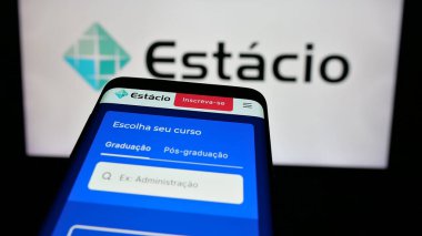Stuttgart, Almanya - 12-16-2024: Brezilyalı eğitim şirketi Estacio SA 'nın web sitesi olan cep telefonu iş logosu önünde ekranda. Telefon ekranının sol üst köşesine odaklan.