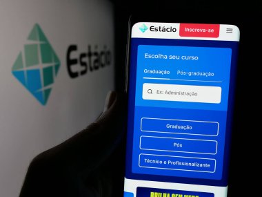Stuttgart, Almanya - 12-16-2024: Brezilyalı eğitim şirketi Estacio SA 'nın internet sayfası olan cep telefonu logosu önünde ekranda. Telefon ekranının merkezine odaklan.