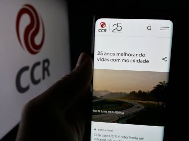 Stuttgart, Almanya - 12-16-2024: Companhia de Concessoes Rodoviarias SA (CCR) adlı şirketin internet sayfası ile cep telefonu bulunduran kişi logo ile ekranda görülüyor. Telefon ekranının merkezine odaklan.