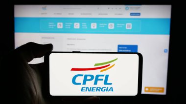 Stuttgart, Almanya - 12-16-2024: Brezilyalı enerji şirketi CPFL Energia SA 'nın logosuyla cep telefonu sahibi kişi iş sayfasının önünde ekranda. Telefon ekranına odaklan.