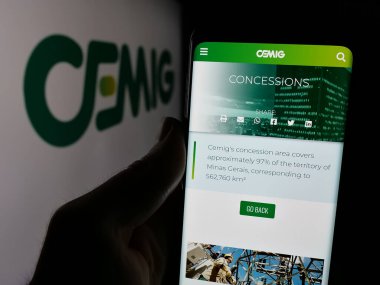 Stuttgart, Almanya - 12-16-2024: Companhia Energetica de Minas Gerais SA 'nın (CEMIG) web sayfası logolu akıllı telefon sahibi kişi. Telefon ekranının merkezine odaklan.