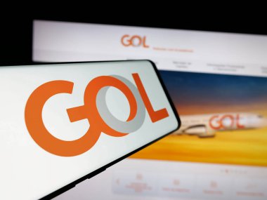 Stuttgart, Germany - 12-18-2024: Cellphone with logo of Brazilian company Gol Linhas Aareas Inteligentes SA on screen in front of website. Focus on center-left of phone display. clipart