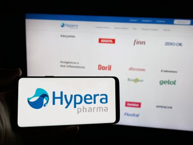 Stuttgart, Almanya - 12-18-2024: Brezilyalı ilaç şirketi Hypera SA 'nın logosunu elinde tutan kişi web sitesinin önünde ekranda. Telefon ekranına odaklan.