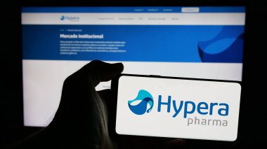 Stuttgart, Almanya - 12-18-2024: Brezilyalı ilaç şirketi Hypera SA 'nın logosunun bulunduğu cep telefonu sahibi kişi iş sayfasının önünde ekranda. Telefon ekranına odaklan.