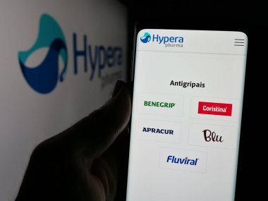 Stuttgart, Almanya - 12-18-2024: Brezilyalı ilaç şirketi Hypera SA 'nın web sayfası ile akıllı telefonu olan kişi iş logosu önünde ekranda. Telefon ekranının merkezine odaklan.