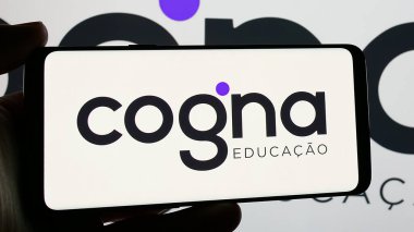 Stuttgart, Almanya - 12-18-2024: Brezilya eğitim şirketi Cogna Educacao SA 'nın logosunu elinde tutan kişi ekranda. Telefon ekranına odaklan.