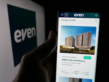 Stuttgart, Almanya - 12-18-2024: Şirketin web sayfası Even Construtora ve Incorporadora SA ile birlikte logo önünde cep telefonu tutan kişi. Telefon ekranının merkezine odaklan.