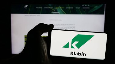 Stuttgart, Almanya - 12-18-2024: Brezilyalı kağıt şirketi Klabin SA 'nın logosuyla cep telefonu sahibi kişi iş sayfasının önünde ekranda. Telefon ekranına odaklan.