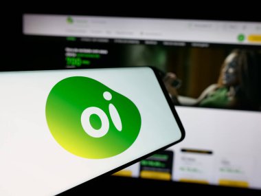 Stuttgart, Germany - 12-19-2024: Cellphone with logo of Brazilian telecommunications company Oi SA on screen in front of business website. Focus on center of phone display. clipart