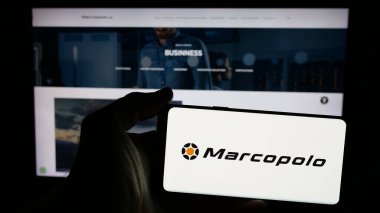 Stuttgart, Almanya - 12-19-2024: Brezilyalı otomotiv şirketi Marcopolo SA 'nın logosuna sahip cep telefonu sahibi kişi iş sayfasının önünde ekranda. Telefon ekranına odaklan.