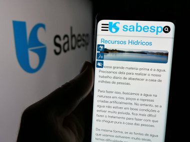 Stuttgart, Almanya - 12-19-2024: Brezilya 'nın atık yönetimi şirketi Sabesp SA' nın web sayfası ile cep telefonu tutan kişi logonun önünde ekranda. Telefon ekranının merkezine odaklan.