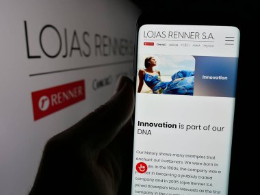 Stuttgart, Almanya - 12-19-2024: Brezilyalı giyim şirketi Lojas Renner SA 'nın internet sayfası ile cep telefonu tutan kişi logonun önünde ekranda. Telefon ekranının merkezine odaklan.