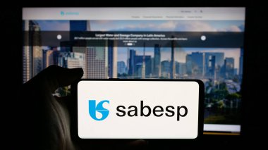 Stuttgart, Almanya - 12-19-2024: Brezilyalı atık yönetim şirketi Sabesp SA 'nın logosunun bulunduğu cep telefonu sahibi kişi iş sayfasının önünde ekranda. Telefon ekranına odaklan.