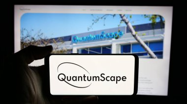 Stuttgart, Germany - 12-20-2024: Person holding cellphone with logo of US battery company QuantumScape Corporation on screen in front of business webpage. Focus on phone display. clipart