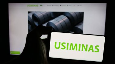 Stuttgart, Almanya - 12-20-2024: Web sayfasının önünde ekranda Usinas Siderurgicas de Minas (Minas Gerais) logosu olan cep telefonu sahibi kişi. Telefon ekranına odaklan.