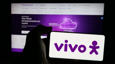 Stuttgart, Almanya - 12-20-2024: Brezilyalı telekomünikasyon şirketi Vivo 'nun logosunun bulunduğu cep telefonu sahibi kişi iş sayfasının önünde ekranda. Telefon ekranına odaklan.
