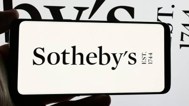 Stuttgart, Almanya - 12-30-2024: İngiliz lüks müzayedeci şirketi Sotheby 'nin logosunu elinde tutan kişi ekranda. Telefon ekranına odaklan.