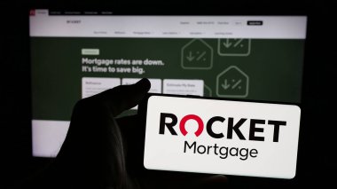 Stuttgart, Almanya - 12-30-2024: Amerikan finans şirketi Rocket Mortgage LLC 'nin logosuna sahip cep telefonu sahibi kişi web sayfasının önünde ekranda. Telefon ekranına odaklan.