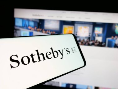 Stuttgart, Germany - 12-30-2024: Smartphone with logo of British luxury auctioneer company Sotheby's on screen in front of business website. Focus on center-left of phone display. clipart