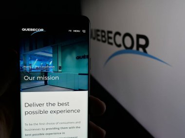 Stuttgart, Almanya - 01-02-2024: Kanadalı telekomünikasyon şirketi Quebecor Inc. 'in web sitesi ile akıllı telefonu elinde tutan kişi logolu ekranda. Telefon ekranının merkezine odaklan.