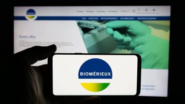 Stuttgart, Almanya - 01-02-2024: Fransız biyoteknoloji şirketi biyoMerieux SA 'nın logosu ile cep telefonu sahibi kişi iş sayfasının önünde ekranda. Telefon ekranına odaklan.