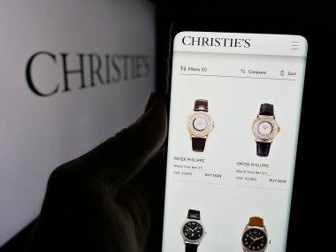 Stuttgart, Almanya - 01-02-2024: İngiliz müzayede şirketi Christie 'nin web sitesi ile akıllı telefon sahibi kişi logonun önünde ekranda. Telefon ekranının merkezine odaklan.