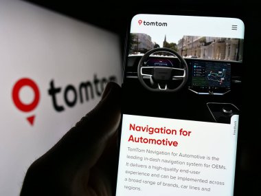 Stuttgart, Almanya - 07-17-2023: Hollandalı konum teknolojisi firması TomTom NV 'nin logolu web sayfası ile akıllı telefonu elinde tutan kişi. Telefon ekranının merkezine odaklan.