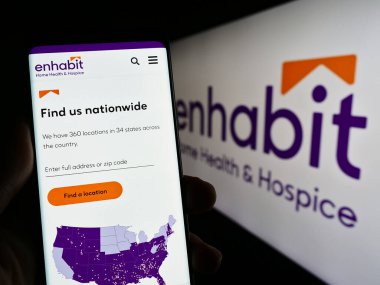 Stuttgart, Almanya - 07-17-2023: Enhabit Home Health and Hospice Corporation sitesinin logolu web sayfasını elinde tutan kişi. Telefon ekranının merkezine odaklan.