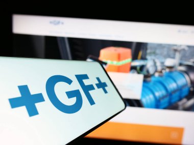 Stuttgart, Almanya - 07-18-2023: İsviçreli Georg Fischer AG (GF) şirketinin logosuna sahip akıllı telefon iş sitesinin önünde ekranda. Telefon ekranının merkezine odaklan.