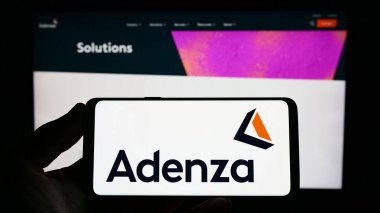 Stuttgart, Almanya - 07-18-2023: Web sitesi önünde ekranda ABD 'li finans yazılım şirketi Adenza Group Inc.' in logosuna sahip akıllı telefonu tutan kişi. Telefon ekranına odaklan.