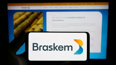 Stuttgart, Almanya - 07-18-2023: Brezilyalı petrokimya şirketi Braskem S.A. 'nın logosunu elinde tutan kişi web sitesinin önünde ekranda. Telefon ekranına odaklan.