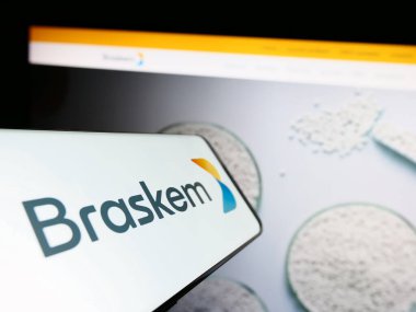 Stuttgart, Germany - 07-18-2023: Mobile phone with logo of Brazilian petrochemical company Braskem S.A. on screen in front of website. Focus on center-right of phone display. clipart