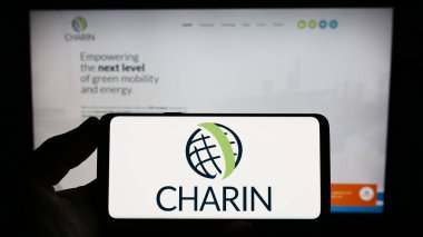 Stuttgart, Almanya - 07-18-2023: Küresel şarj derneği CharIN E.V. logosuna sahip akıllı telefon sahibi kişi Web sitesinin önünde ekranda. Telefon ekranına odaklan.