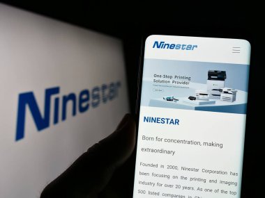 Stuttgart, Almanya - 07-18-2023: Çinli yazıcı şirketi Ninestar Corporation 'ın internet sitesiyle cep telefonu tutan kişi logolu ekranda. Telefon ekranının merkezine odaklan.