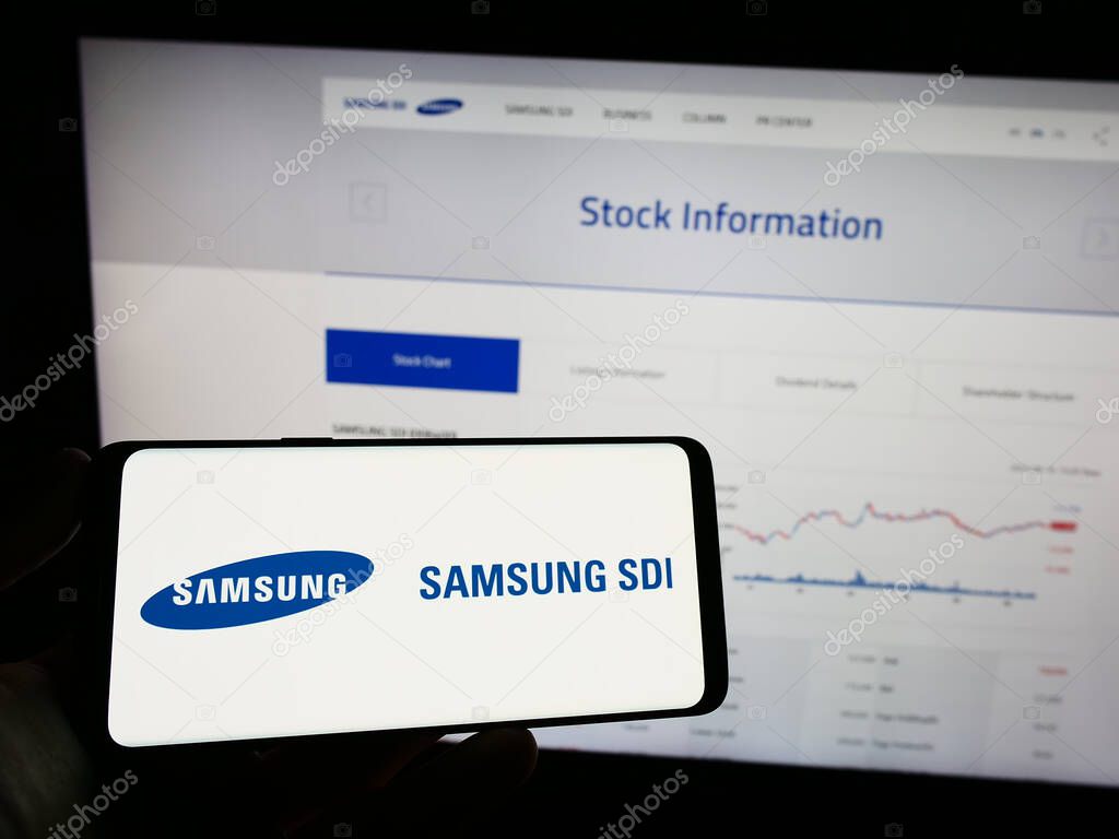 Stuttgart, Germany - 07-17-2023: Person holding mobile phone with logo of electronics company Samsung SDI Co. Ltd. on screen in front of business web page. Focus on phone display.