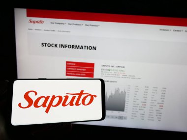Stuttgart, Almanya - 07-18-2023: Kanadalı mandıra şirketi Saputo Inc. 'nin logosunu taşıyan cep telefonu sahibi iş sayfasının önünde ekranda. Telefon ekranına odaklan.