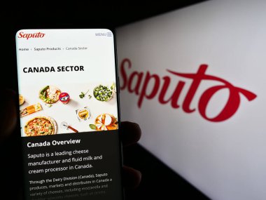Stuttgart, Almanya - 07-18-2023: Kanadalı mandıra şirketi Saputo Inc. 'nin web sitesi ile cep telefonu tutan kişi logonun önünde ekranda. Telefon ekranının merkezine odaklan.