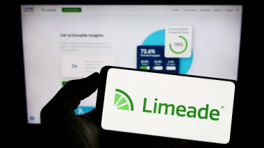 Stuttgart, Germany - 06-18-2023: Person holding cellphone with logo of US employee well-being company Limeade Inc. on screen in front of business webpage. Focus on phone display. clipart