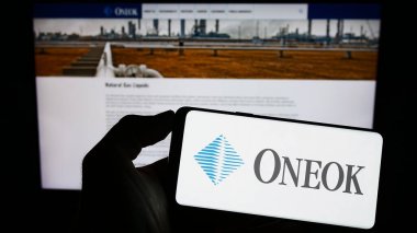 Stuttgart, Almanya - 06-18-2023: Amerikan doğalgaz şirketi Oneok Inc. 'in logosuna sahip cep telefonu sahibi kişi iş sayfasının önünde ekranda. Telefon ekranına odaklan.