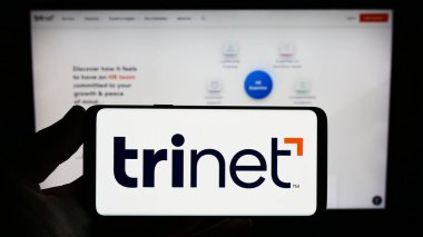 Stuttgart, Almanya - 06-18-2023: ABD 'li dış kaynak şirketi TriNet Group Inc.' in logosuna sahip kişi web sitesinin önünde ekranda. Telefon ekranına odaklan.