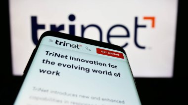 Stuttgart, Almanya - 06-18-2023: Smartphone ve ABD 'li dış kaynak şirketi TriNet Group Inc.' in web sayfası iş logosu önünde ekranda. Telefon ekranının sol üst kısmına odaklan.