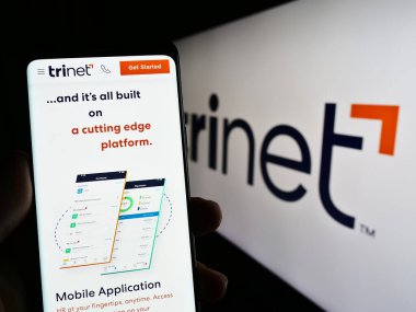 Stuttgart, Almanya - 06-18-2023: ABD 'li taşeronluk şirketi TriNet Group Inc.' in web sayfası olan cep telefonu logonun önünde ekranda. Telefon ekranının merkezine odaklan.