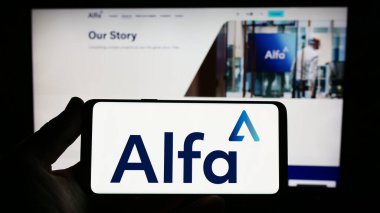 Stuttgart, Almanya - 06-18-2023: İnternet sitesi önünde ekranda Alfa Financial Software Holding plc şirketinin logosuna sahip akıllı telefon sahibi kişi. Telefon ekranına odaklan.